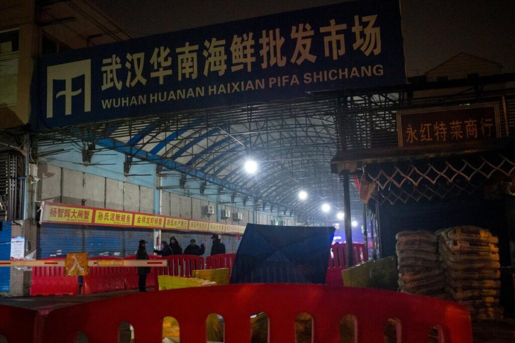 Security guards stand in front of the main warehouse at night.